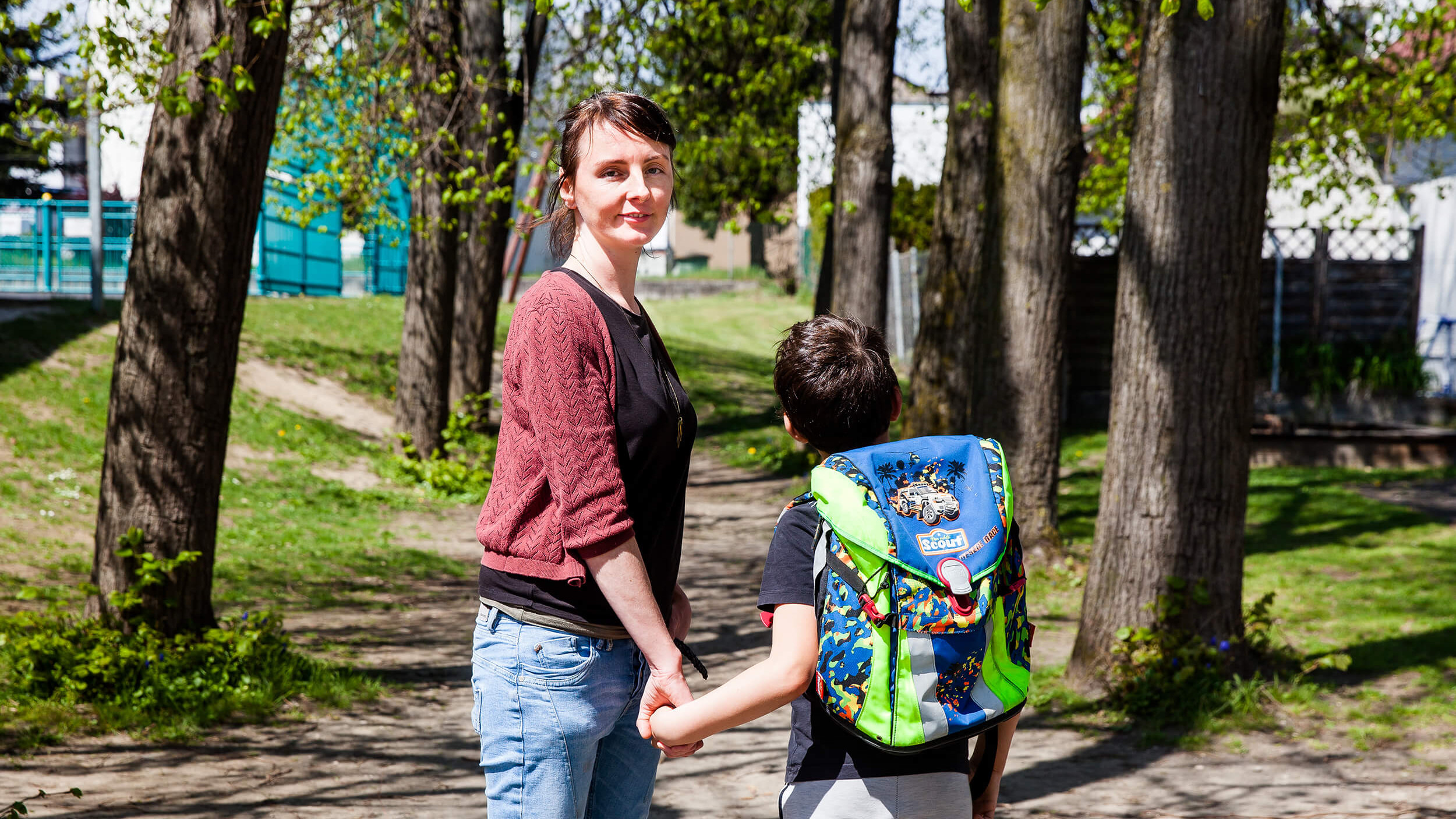 Ein Kind mit Schultasche und eine Frau auf einem Weg