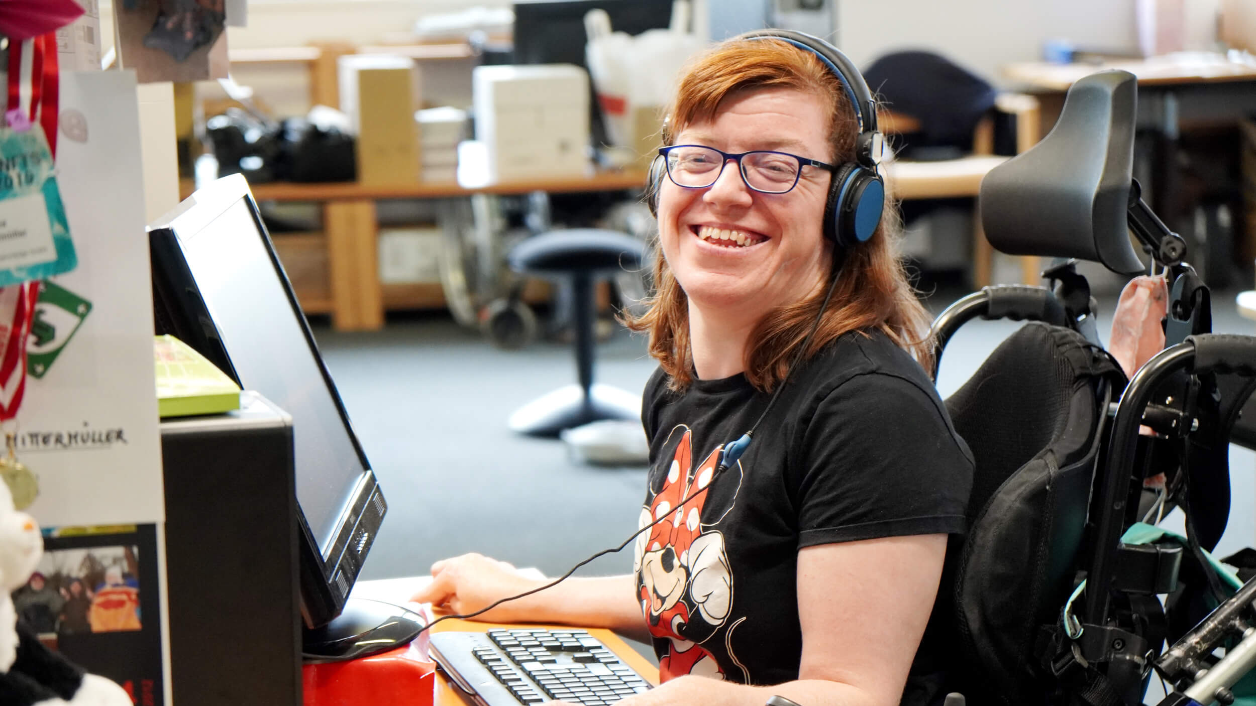 Eine Frau im Rollstuhl am Arbeitsplatz in der EDV-Werkstätte Hagenberg.